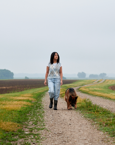 woman walking through field with dog