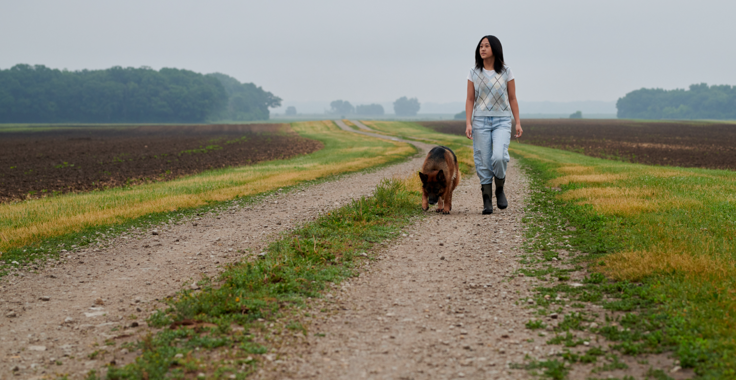 woman with dog walking through field